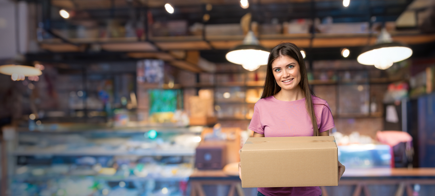 Rapariga num armazém com uma encomenda nas mãos