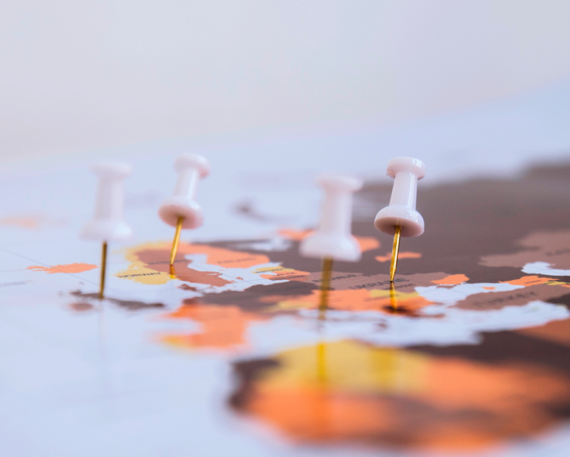 mapa mundo com alfinetes colocados sobre alguns paises.